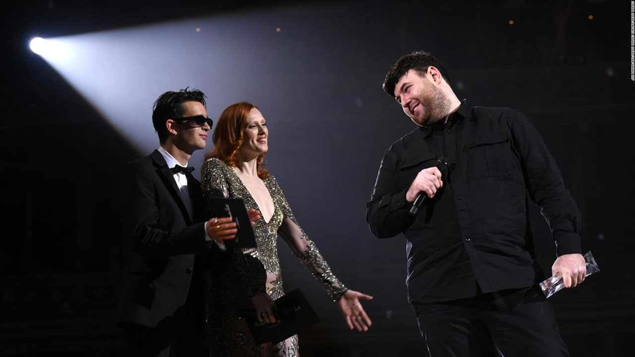 Richard Quinn, ITS 2015 finalist, accepts the British Emerging Talent Womenswear Award from model Karen Elson and The 1975 frontman Matthew Healy at The Fashion Award 2018