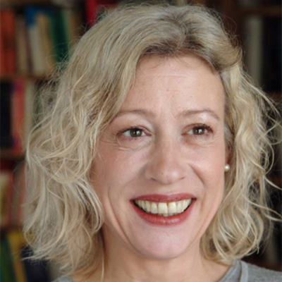 a woman with blonde hair smiling in front of a bookshelf