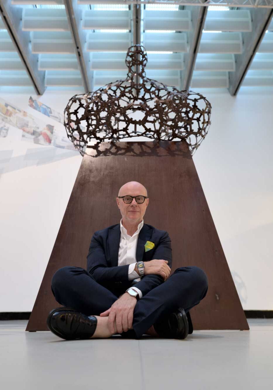 a man sitting on the floor in front of a sculpture