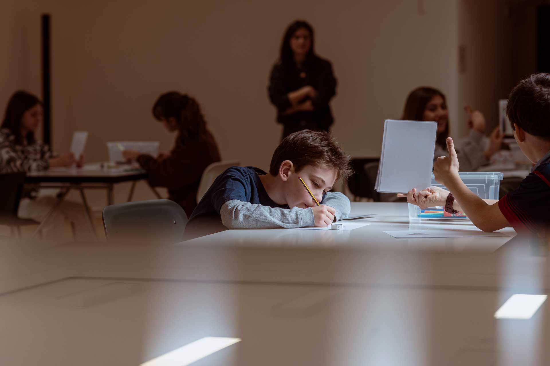 two boys sitting at a table with papers and pens