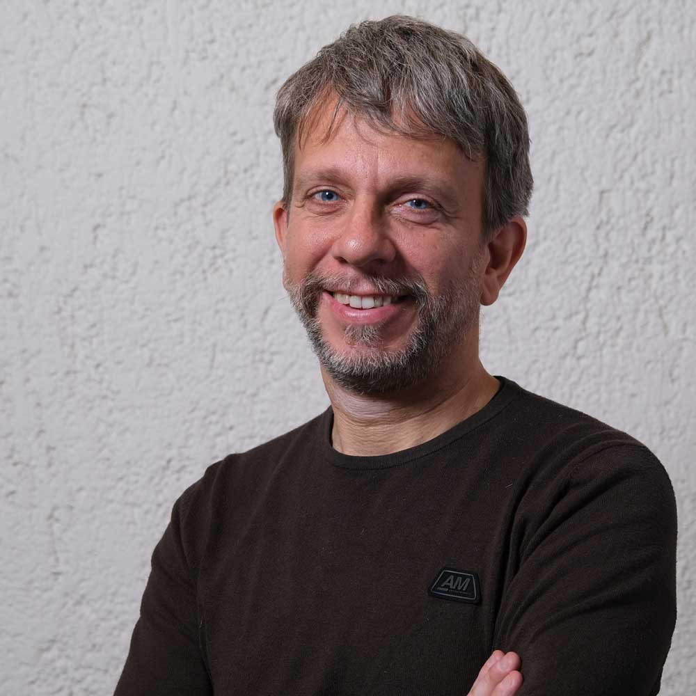 a man with his arms crossed standing in front of a white wall