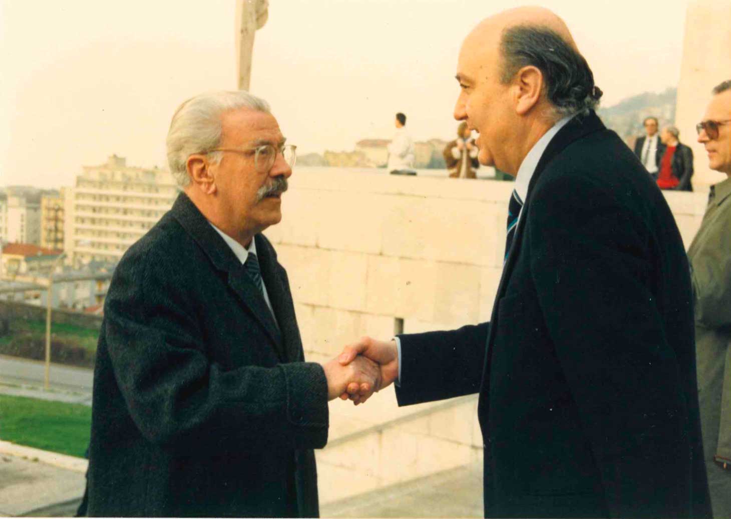 two men shaking hands while standing next to each other